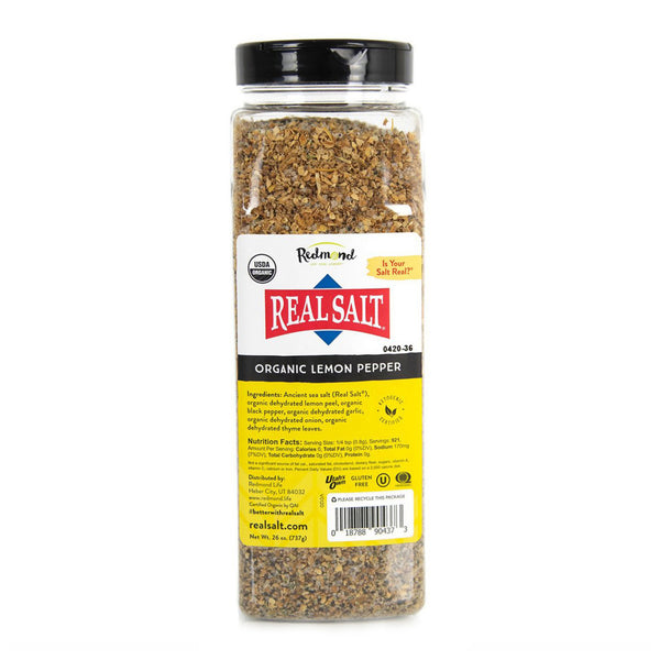 A clear jar displays Redmond Real Salt's Organic Lemon Pepper seasoning, featuring a blend of ancient sea salt, lemon peel, black pepper, garlic, onion, and thyme. 
