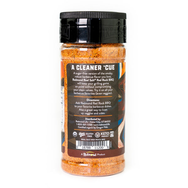 Clear jar displays Redmond Real Salt Red Rock BBQ seasoning with a black lid against a white background. 
